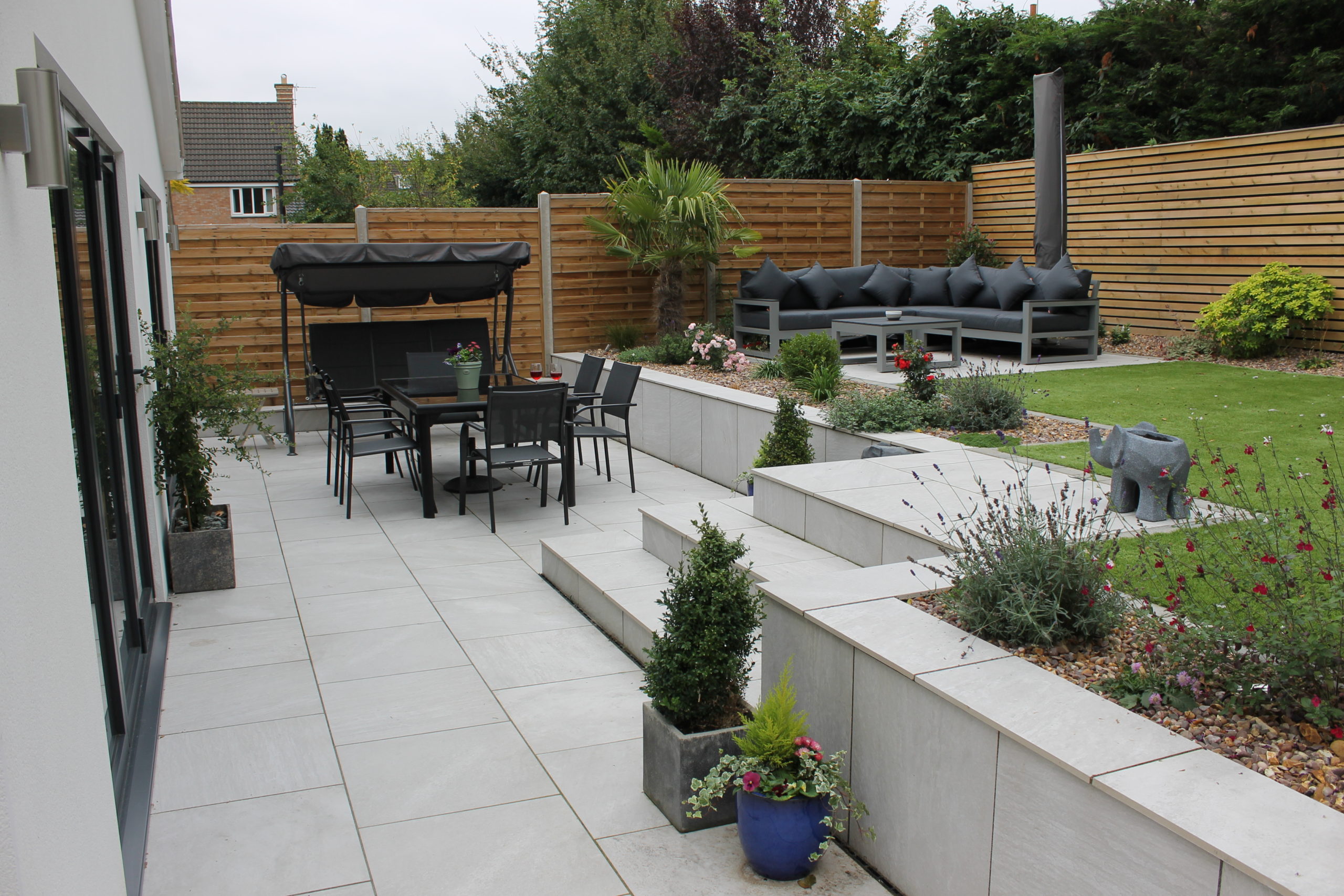 Porcelain paved garden with black table chairs and couch