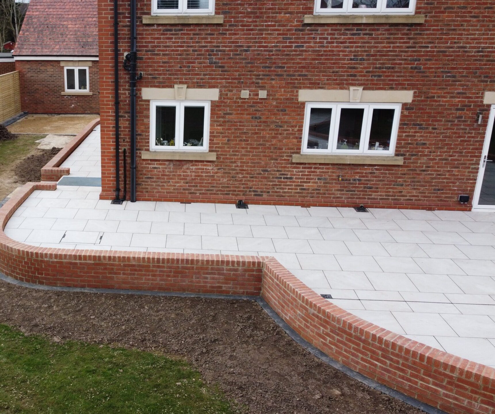 White patio wrapping around a red brick house