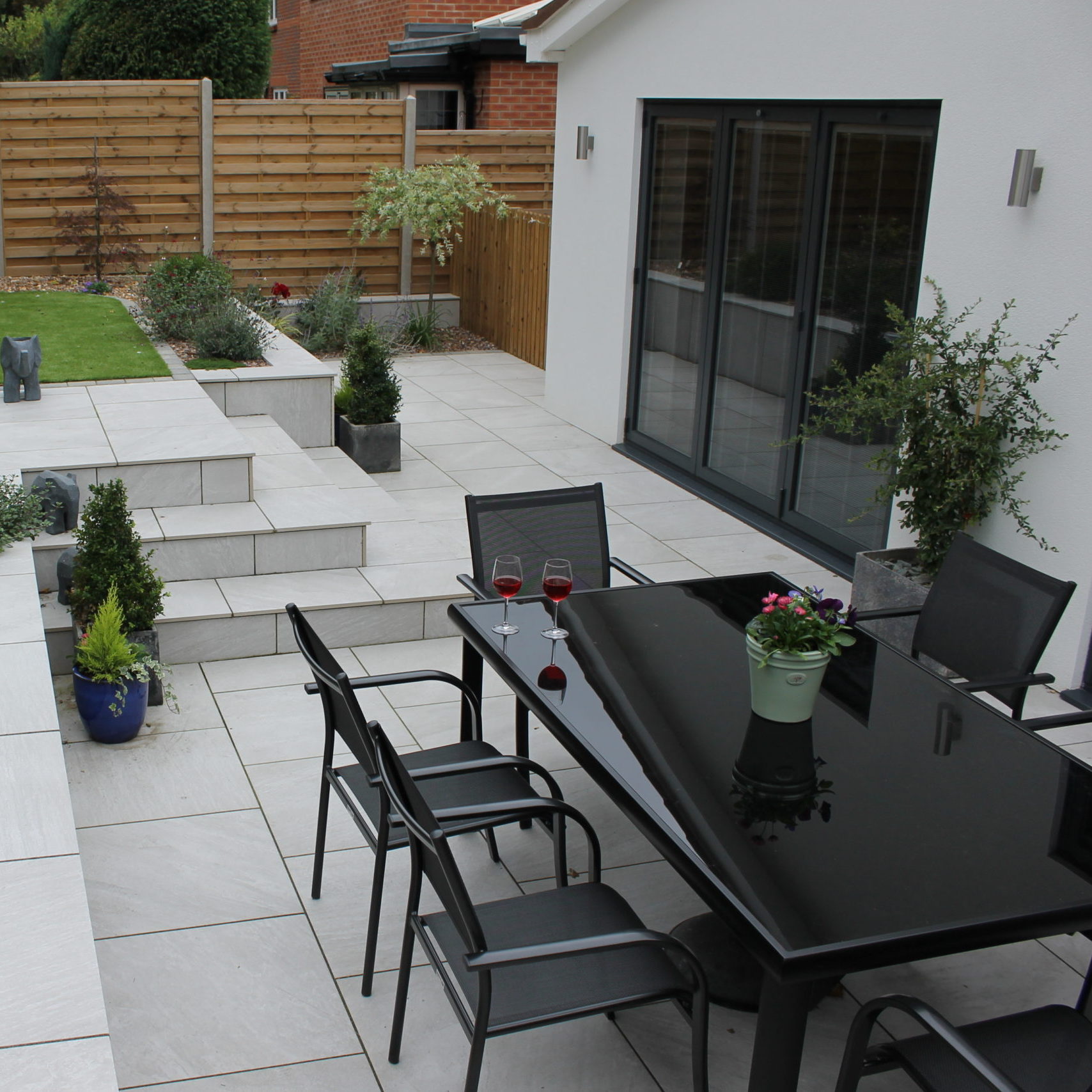 White Patio with black garden furniture and raised grass